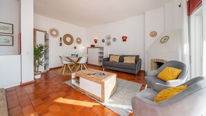 Een woonkamer met een bank, fauteuil, salontafel en een open haard.