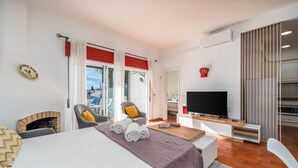Een hotelkamer met een bed, een televisie, een open haard en een balkon met uitzicht.