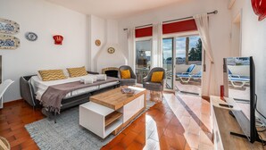 Een moderne woonkamer met een bank, salontafel en stoelen, een open haard en uitzicht op de natuur.