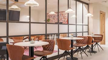Un espace repas moderne avec des tables rondes et des chaises recouvertes d’un tissu marron.