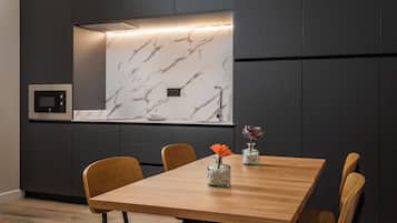 A modern dining area with a marble backsplash, a built-in oven, and a wooden dining table with chairs.