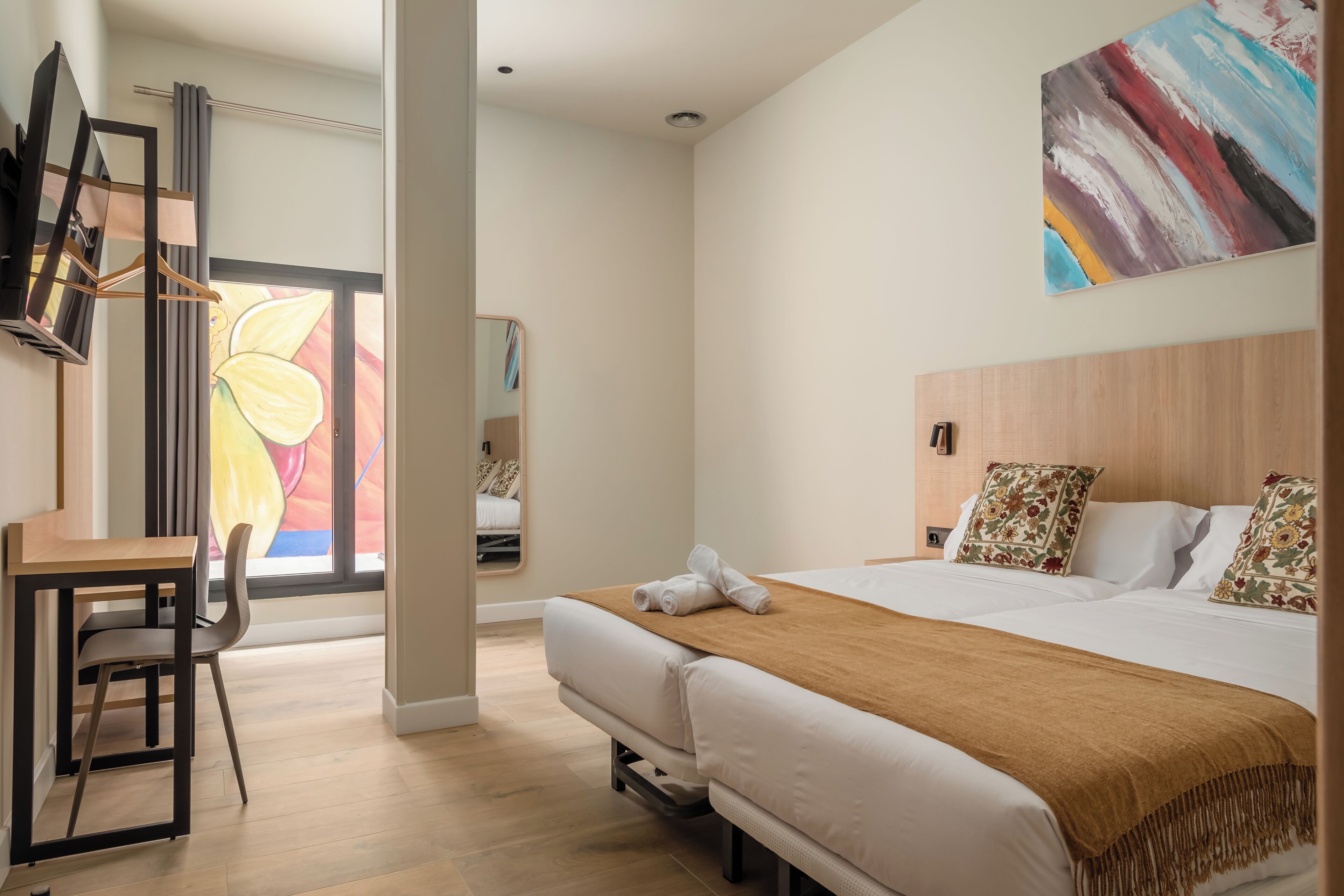 A modern hotel room with a bed, a desk, and a chair.