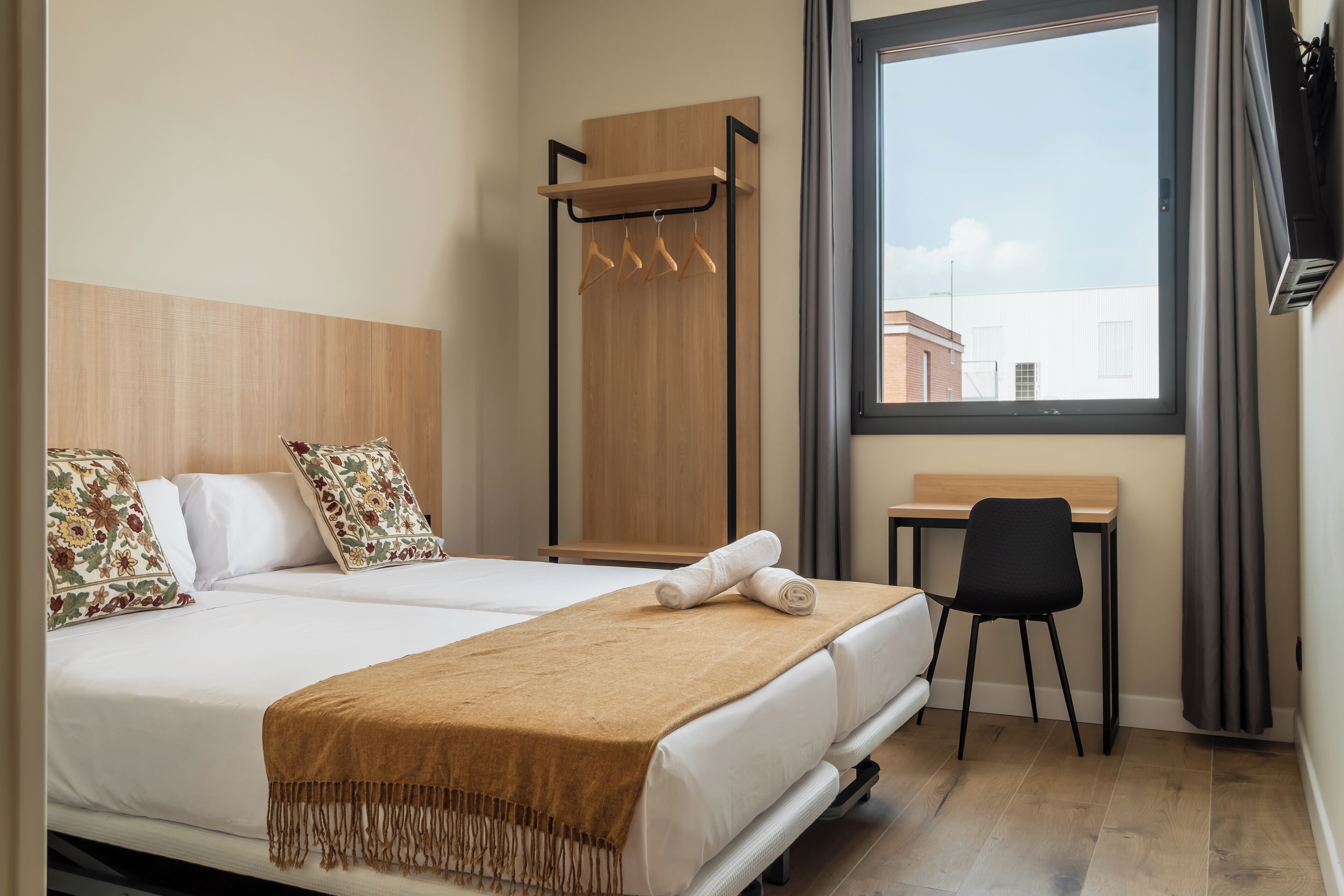 Een hotelkamer met een bed, een bureau en een raam met gordijnen.