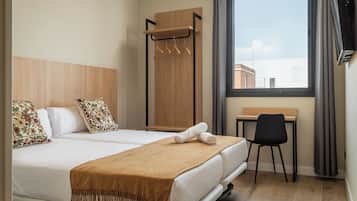 Habitación de hotel con cama, escritorio y ventana con cortinas.