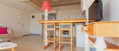 Una cocina moderna con armarios blancos, una mesa de comedor de madera y una lámpara roja.