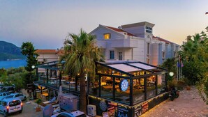 A modern building with a glass facade, a sign for "Kalkan Suites," and a view of the sea. - Kalkan Suites Hotel (Kas)