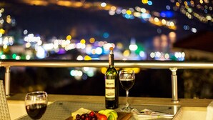 A table with a bottle of wine, two glasses, a bowl of olives, and a wooden board with tomatoes and grapes. - Kalkan Suites Hotel (Kas)