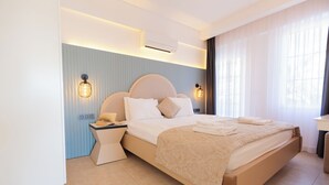 A modern hotel room with a large bed, bedside lamps, and a window with sheer curtains. - Kalkan Suites Hotel (Kas)