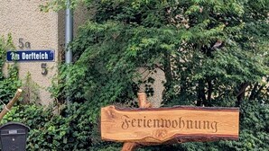 Een houten bord met de tekst 'Ferienwohnung', dat wijst op een vakantiewoning.