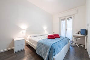 Una camera da letto con un letto, un comodino, una scrivania e un computer.