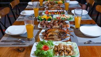 A dining table set with plates of seafood, salads, and drinks.