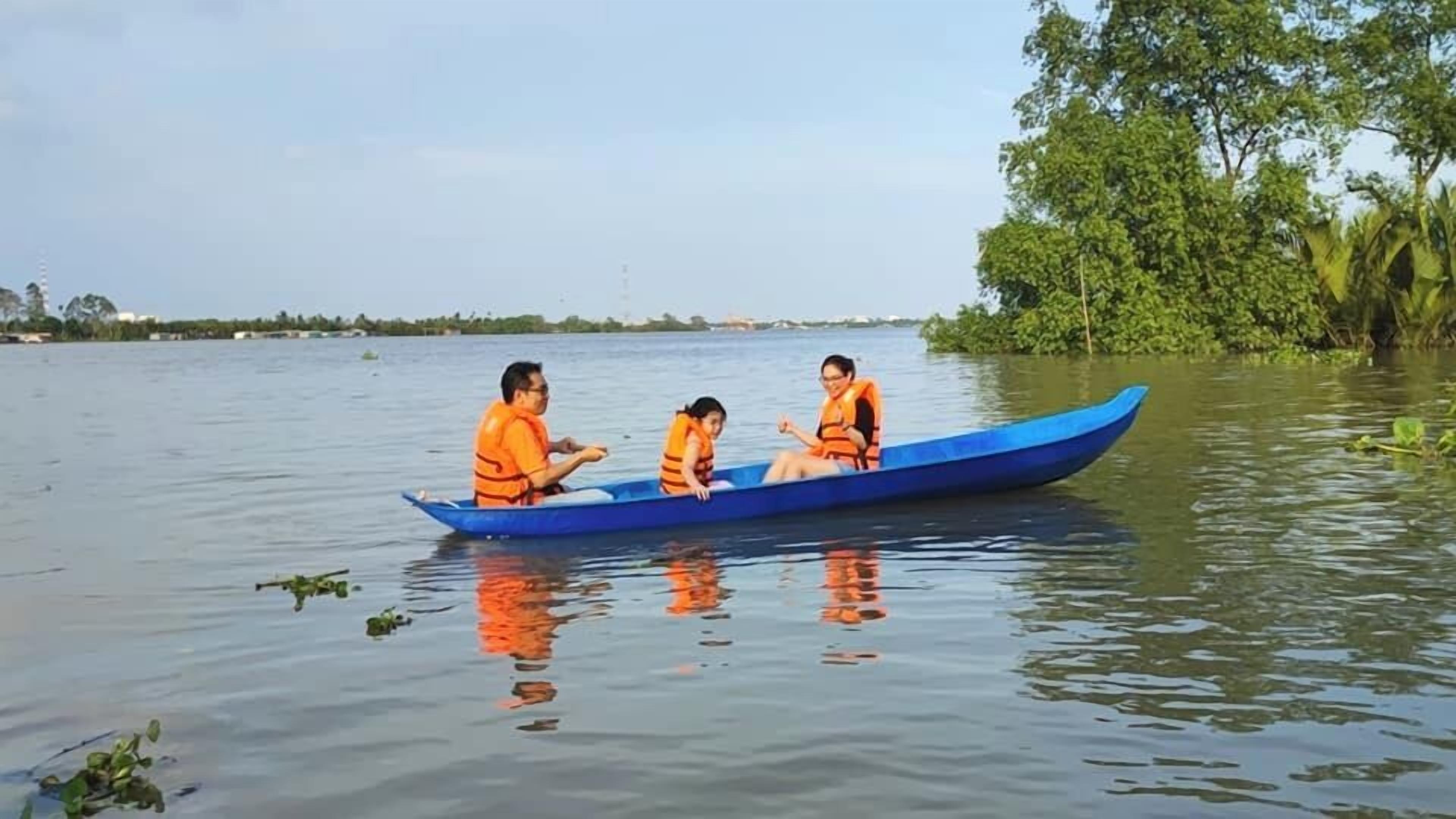 Eine Gruppe von Menschen in einem blauen Boot auf ruhigem Wasser, umgeben von viel Grün.