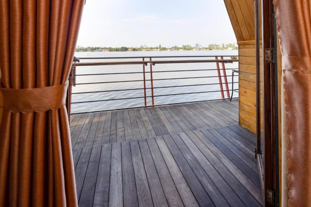 Een houten terras met een metalen hekwerk, uitkijkend op een wateroppervlak.