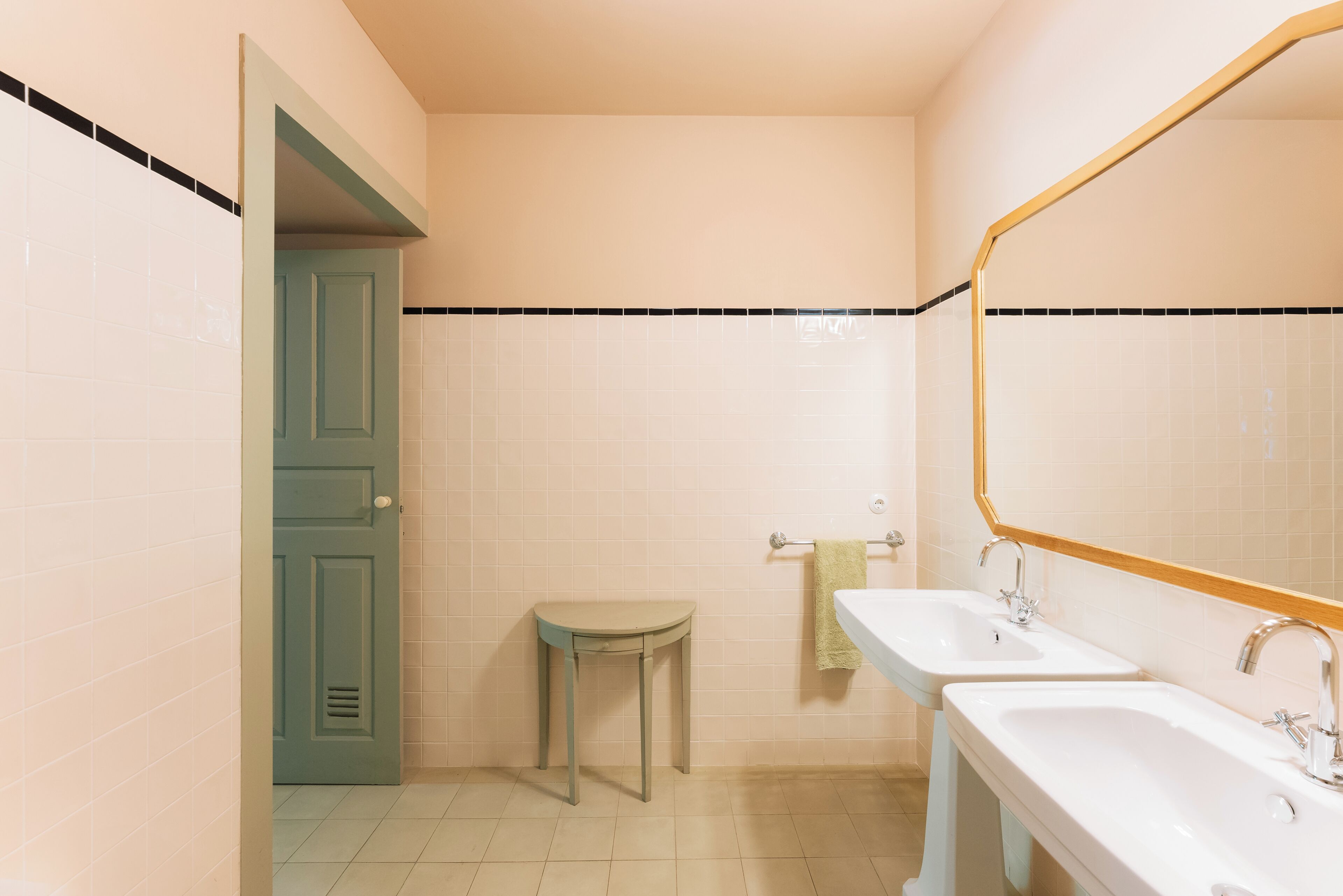 A bathroom with two sinks, a mirror, and a door leading to another room.
