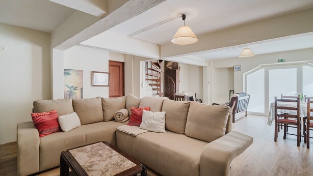 A spacious living area with a sofa, a coffee table, a staircase, and a dining area.