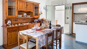 Un coin repas avec un buffet en bois, une table dressée avec des assiettes, des verres et un vase de fleurs.