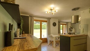A modern kitchen with a wooden countertop, a dining area with a table and chairs, and a large window with curtains.