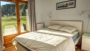 A bedroom with a bed, a nightstand, a lamp, and a window with curtains.