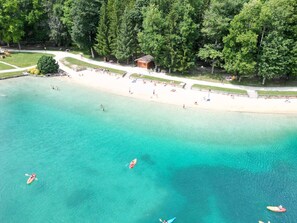 An aerial view of a beach with clear turquoise water, kayaks, and people. - Renovated apartment with WiFi near ski-bus (Morillon Village)