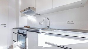 A modern kitchen with a stainless steel range hood, a built-in oven, and a sleek countertop. - SMS Homes I time out in Blaichach (Blaichach)