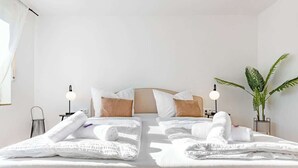 A hotel room with a bed, two bedside lamps, a potted plant, and a window with curtains. - SMS Homes I time out in Blaichach (Blaichach)