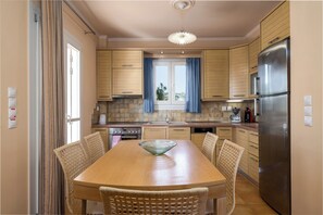 Enjoy cooking in this kitchen with a central island, oven, and wicker chairs.