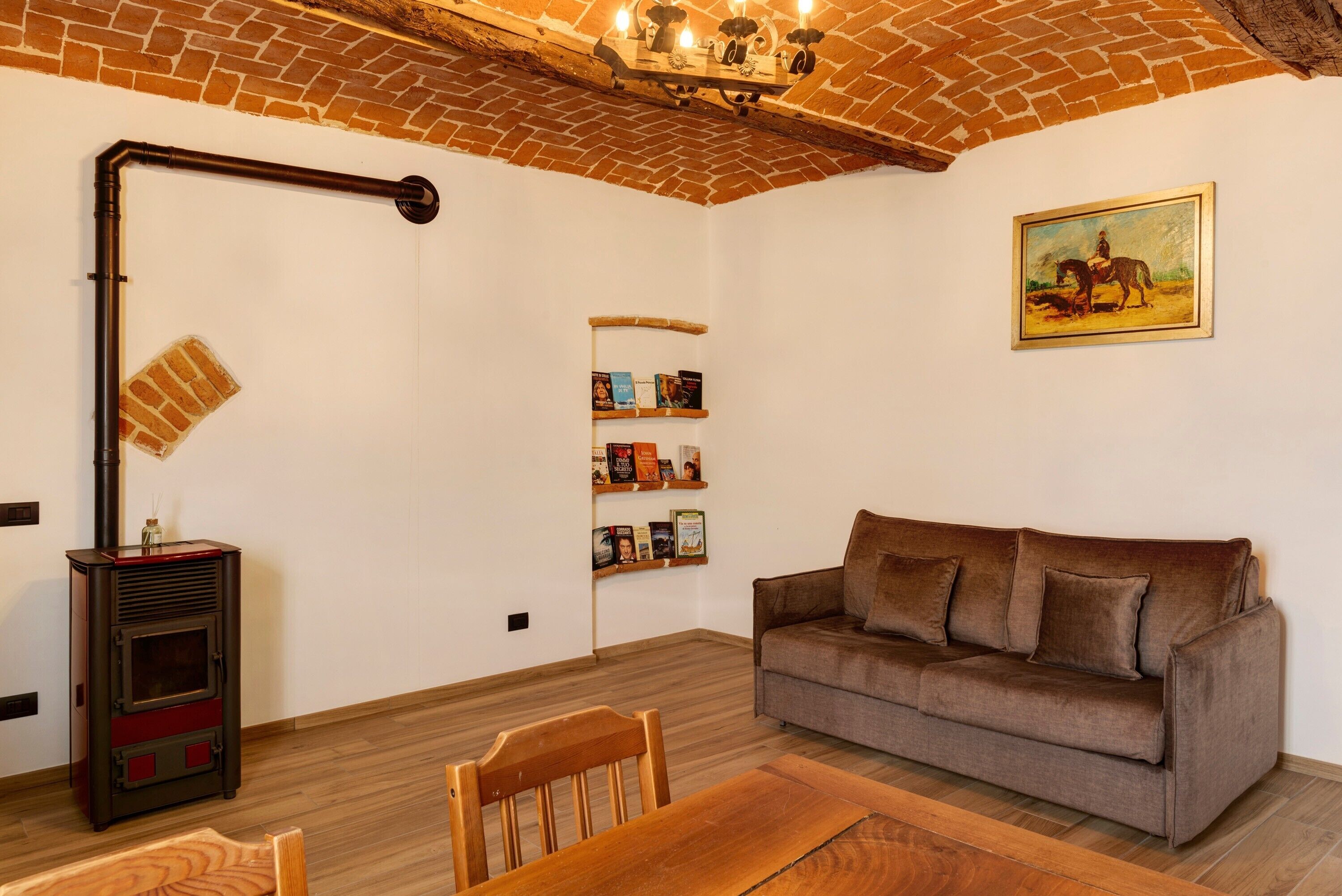 A living room with a brick ceiling, a sofa, a table, a bookshelf, and a fireplace.