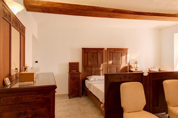 A bedroom with a wooden bed, a nightstand, a dresser, and a mirror.