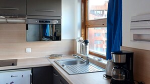 Une cuisine compacte équipée d’un four encastré, d’un évier et d’une machine à café.