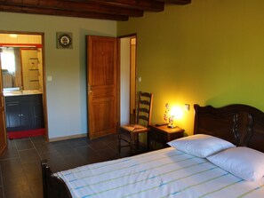 A bedroom with a bed, a nightstand, a chair, a desk, and a bathroom visible through an open door. - Cozy B&B near Luxembourg and Belgium (Xivry-Circourt)