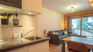 A modern kitchen with a stainless steel sink and a dining area with a wooden table and chairs. - Valmorel: Apt for 6, 2 bdrm, parking, wifi, ski-in/ski-out (Valmorel)