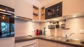 A modern kitchen with built-in appliances, wooden cabinets, and a window with a view of trees. - Valmorel: Apt for 6, 2 bdrm, parking, wifi, ski-in/ski-out (Valmorel)