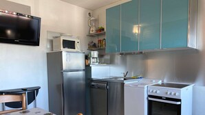 A compact kitchen with a refrigerator, microwave, dishwasher, stove, and a small sink.