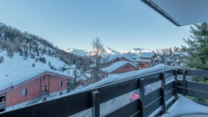 A snow-covered mountain village with wooden buildings and a clear view of the mountains.