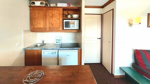 A compact kitchen with wooden cabinets, a microwave, a coffee maker, and a dishwasher. - 3-room apartment, ski-in/ski-out, sleeps 7, Plagne Soleil (Plagne Soleil)