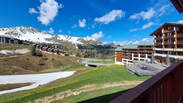 A mountain resort with wooden buildings, a ski lift, and a clear view of snow-capped mountains. - 3-room apartment, ski-in/ski-out, sleeps 7, Plagne Soleil (Plagne Soleil)