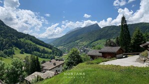 A mountainous village with traditional houses, a clear sky, and lush greenery.