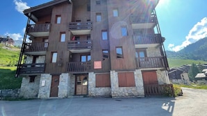 A multi-story building with balconies, stone base, and a sign indicating a restaurant.