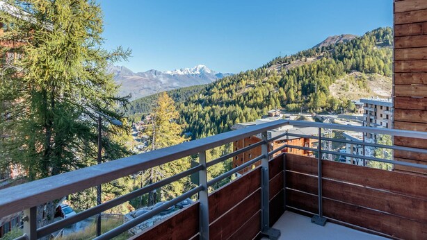A balcony with a view of a mountainous landscape, including snow-capped peaks and dense forest. - 2-room apartment with balcony and garage, 100m from slopes (La Plagne-Tarentaise)