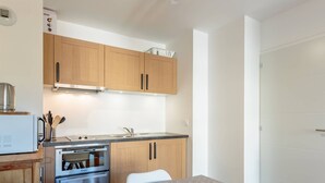 A compact kitchen with wooden cabinets, a built-in oven, and a microwave. - 2-room apartment with balcony and garage, 100m from slopes (La Plagne-Tarentaise)