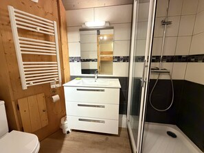 Ein Badezimmer mit einem weißen Waschbecken, einem Spiegel und einer Duschkabine aus Glas.