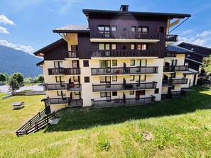 A multi-story building with balconies, a flat roof, and a grassy area in front. - 2-Room Duplex for 6 in Vallandry - Pets Allowed (Peisey-Vallandry)