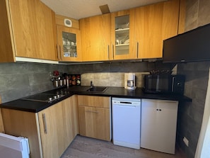 A compact kitchen with wooden cabinets, a black countertop, a coffee maker, a microwave, and a dishwasher. - 2-Room Duplex for 6 in Vallandry - Pets Allowed (Peisey-Vallandry)
