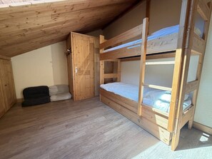 Ein Zimmer mit einem Holzbett mit zwei Etagen, einer Tür und einer kleinen Couch.