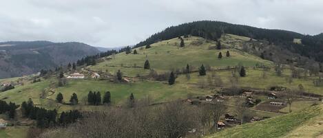 A rural landscape with rolling hills, scattered houses, and a dirt road.