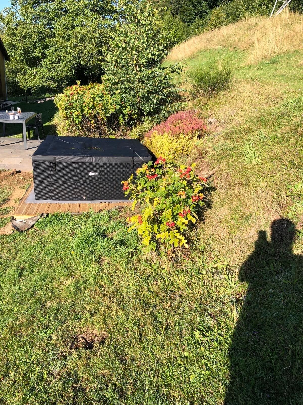 A garden area with a covered outdoor seating area and a large black storage unit.