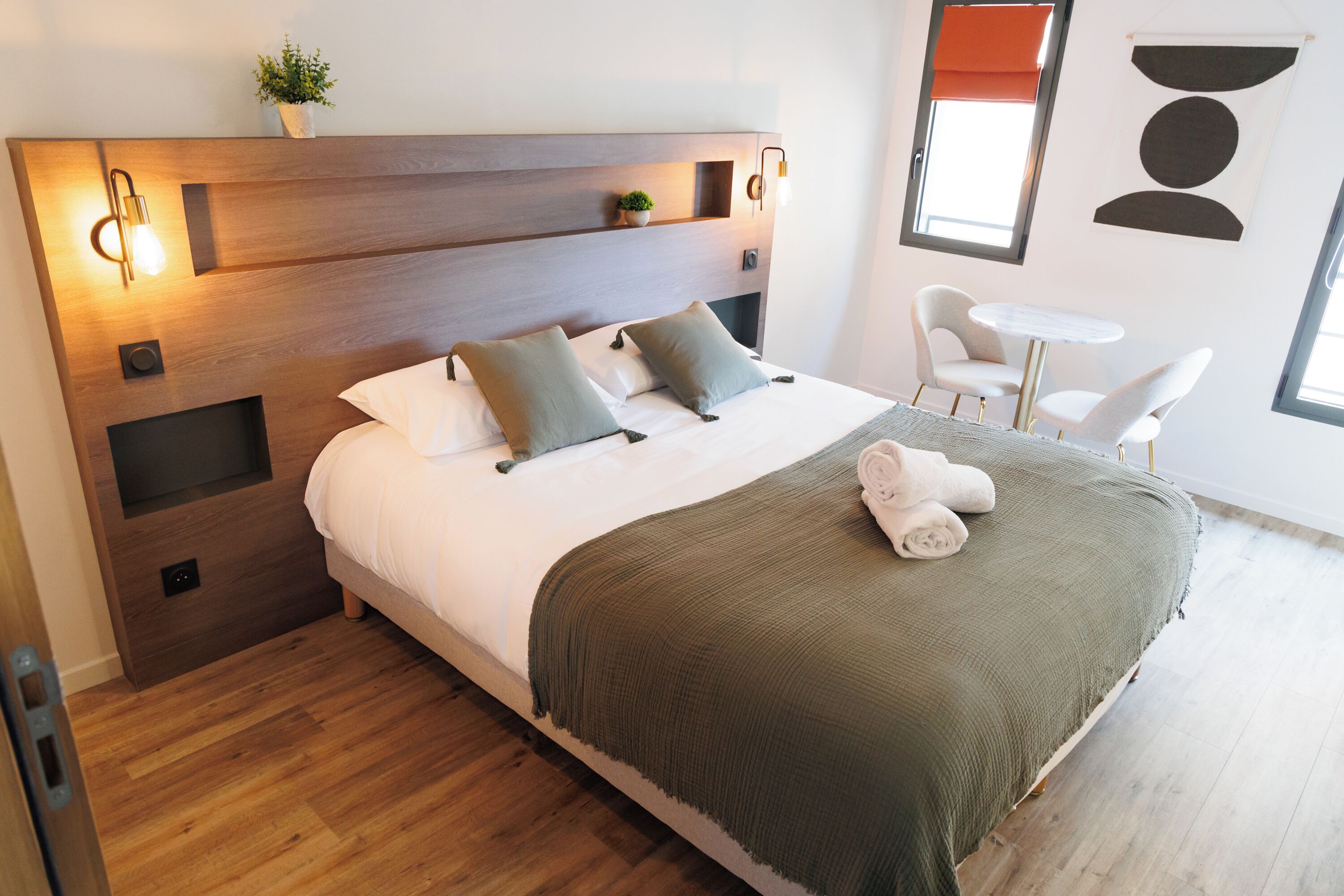 A modern hotel room with a large bed, a small desk, and a chair.