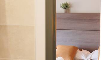 Habitación de hotel con cama, cabecera, planta pequeña y una toalla en el suelo.