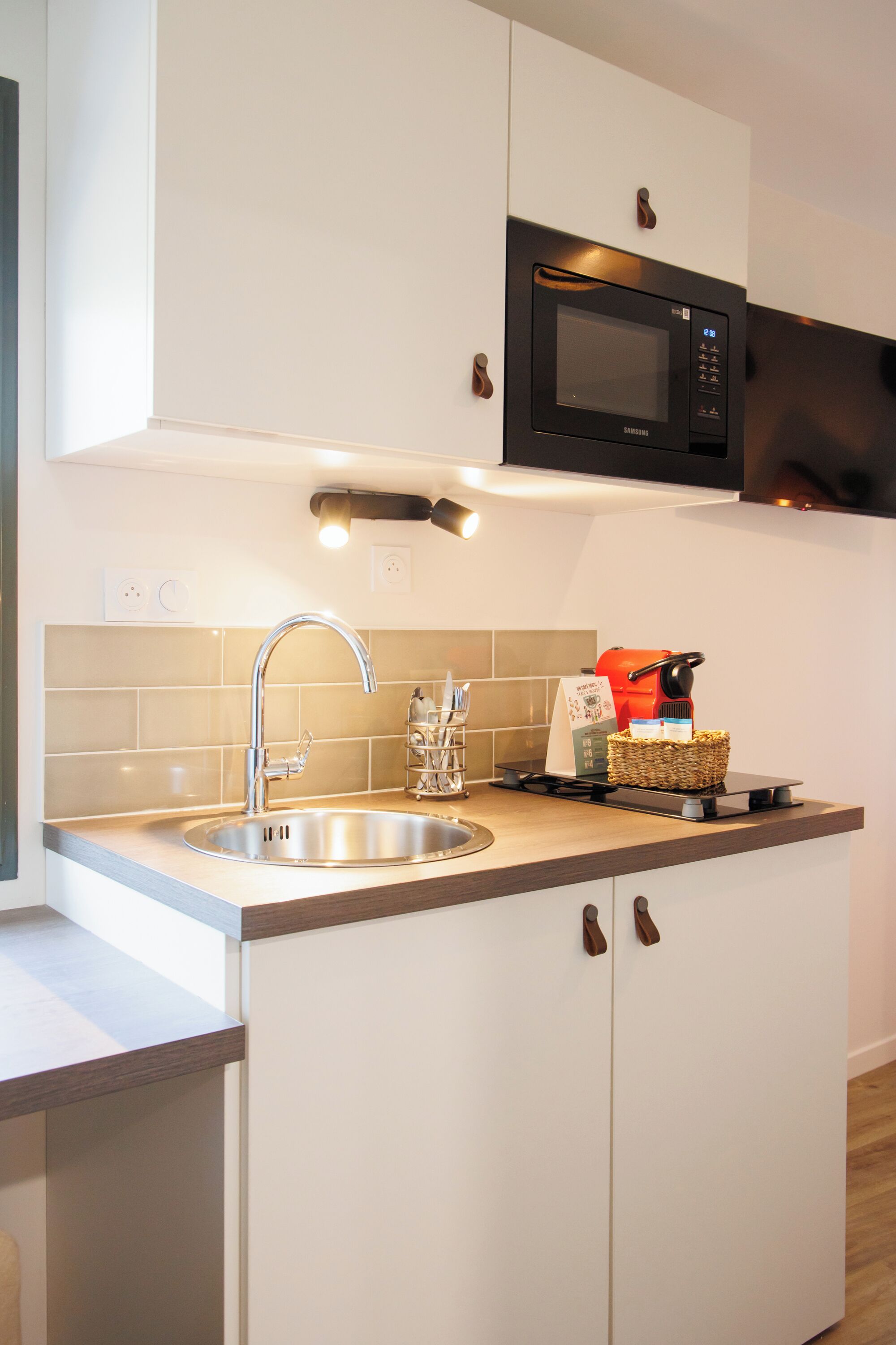 A modern kitchen with a stainless steel sink, a microwave, and a coffee machine.