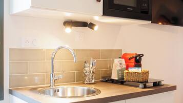 Una cocina moderna con un lavamanos de acero inoxidable, un microondas y una cafetera.